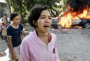 Frightened East Timorese pass by a burning car after hiding in a burning house from a mob attack Saturday, May 27, 2006